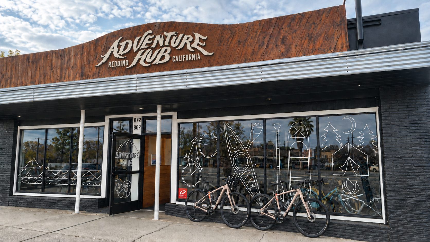 Adventure Hub signage visualization based on the real storefront, with the supplied logo, original window illustrations, and bicycles.